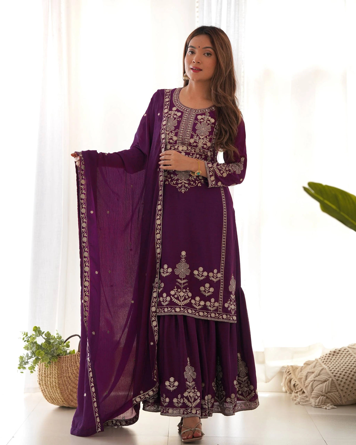 Woman wearing a purple embroidered traditional outfit with a white background