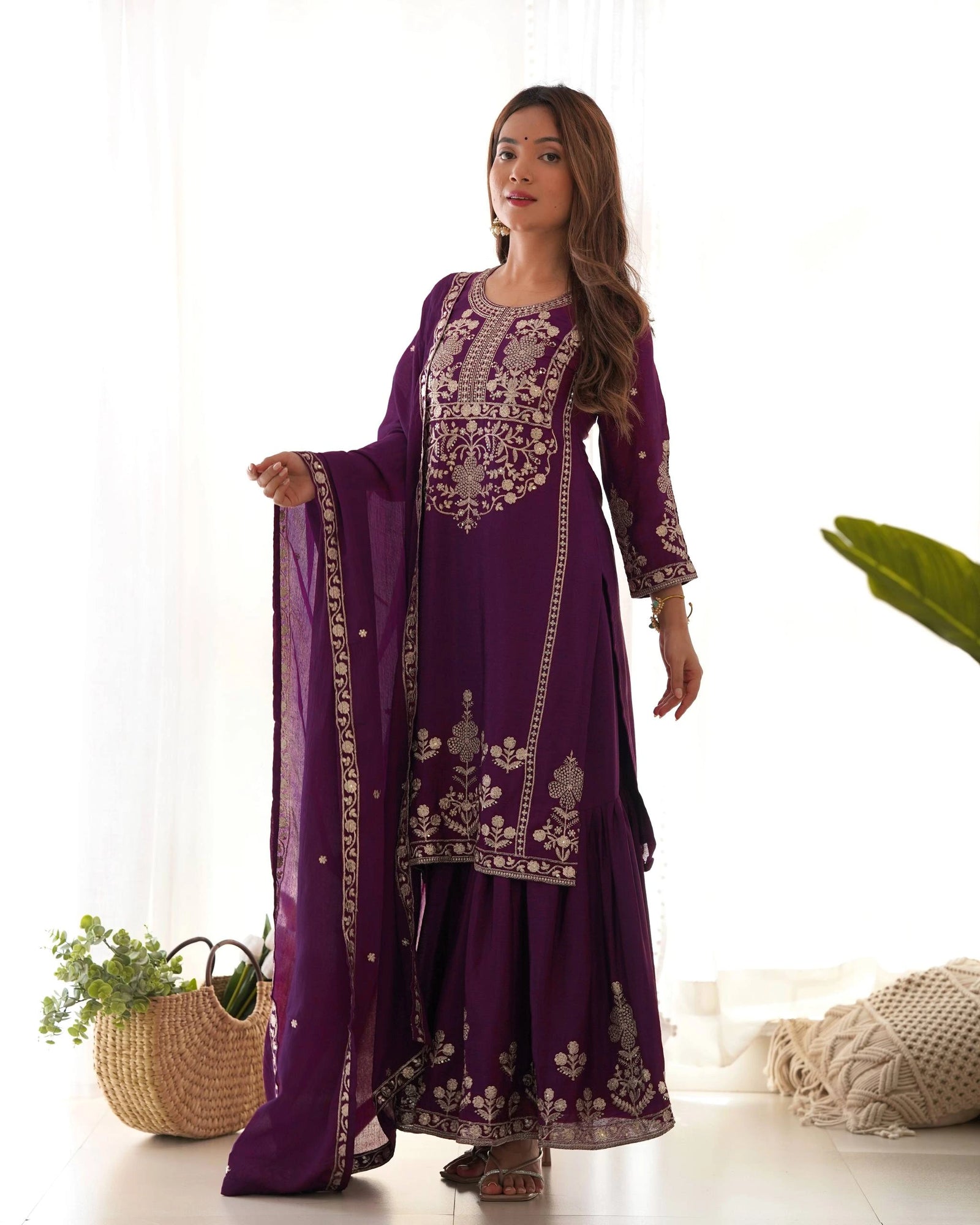 Woman wearing a purple embroidered traditional outfit with a white background