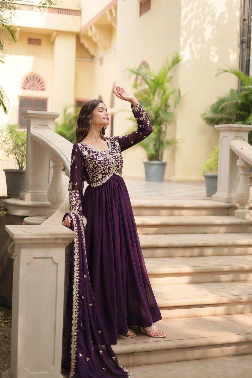 Woman in a purple traditional outfit standing on steps outdoors.