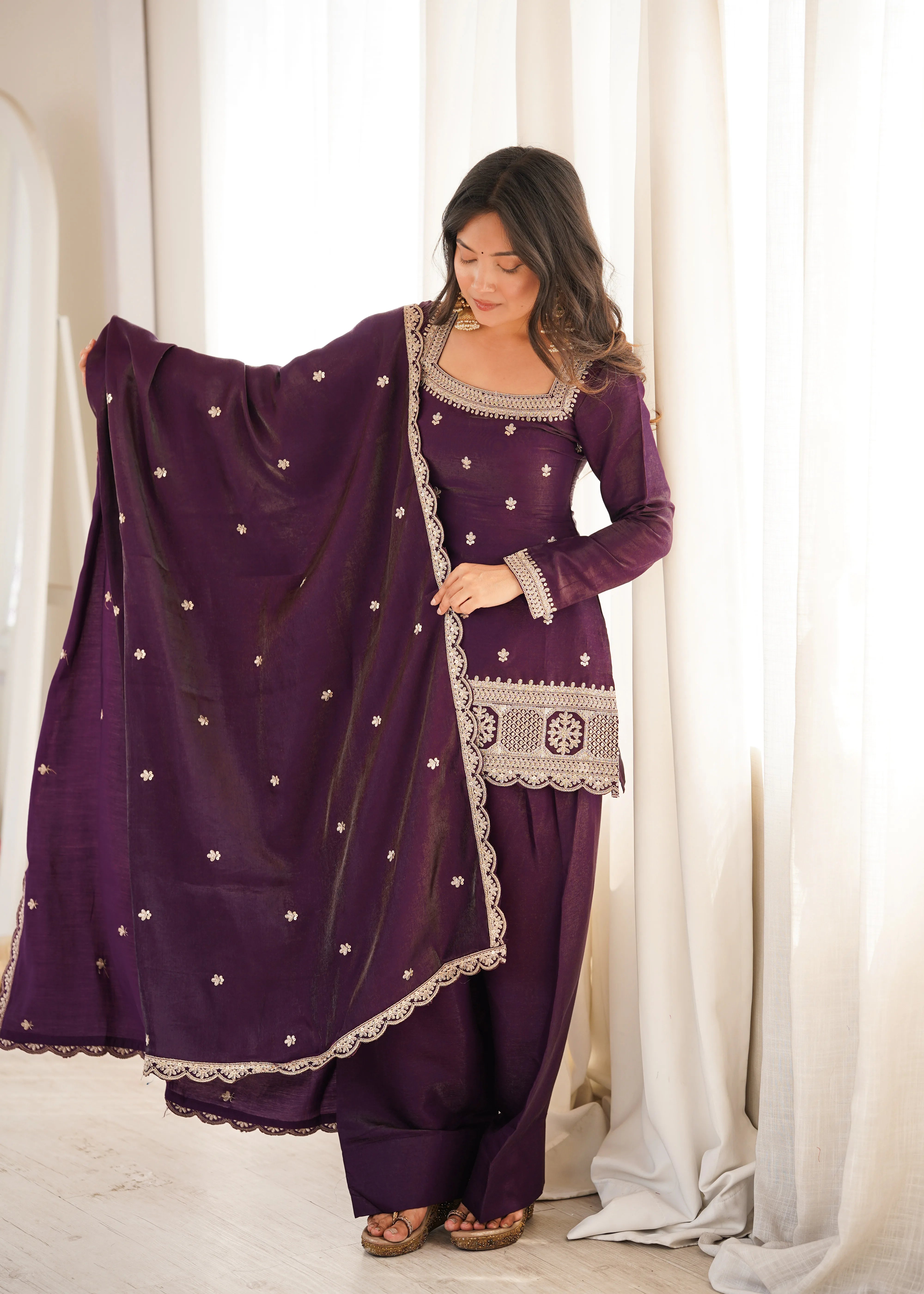 She gracefully drapes a matching sheer dupatta adorned with delicate embellishments.