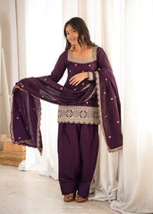 Woman in a traditional outfit with a purple dress and dupatta against a white curtain background