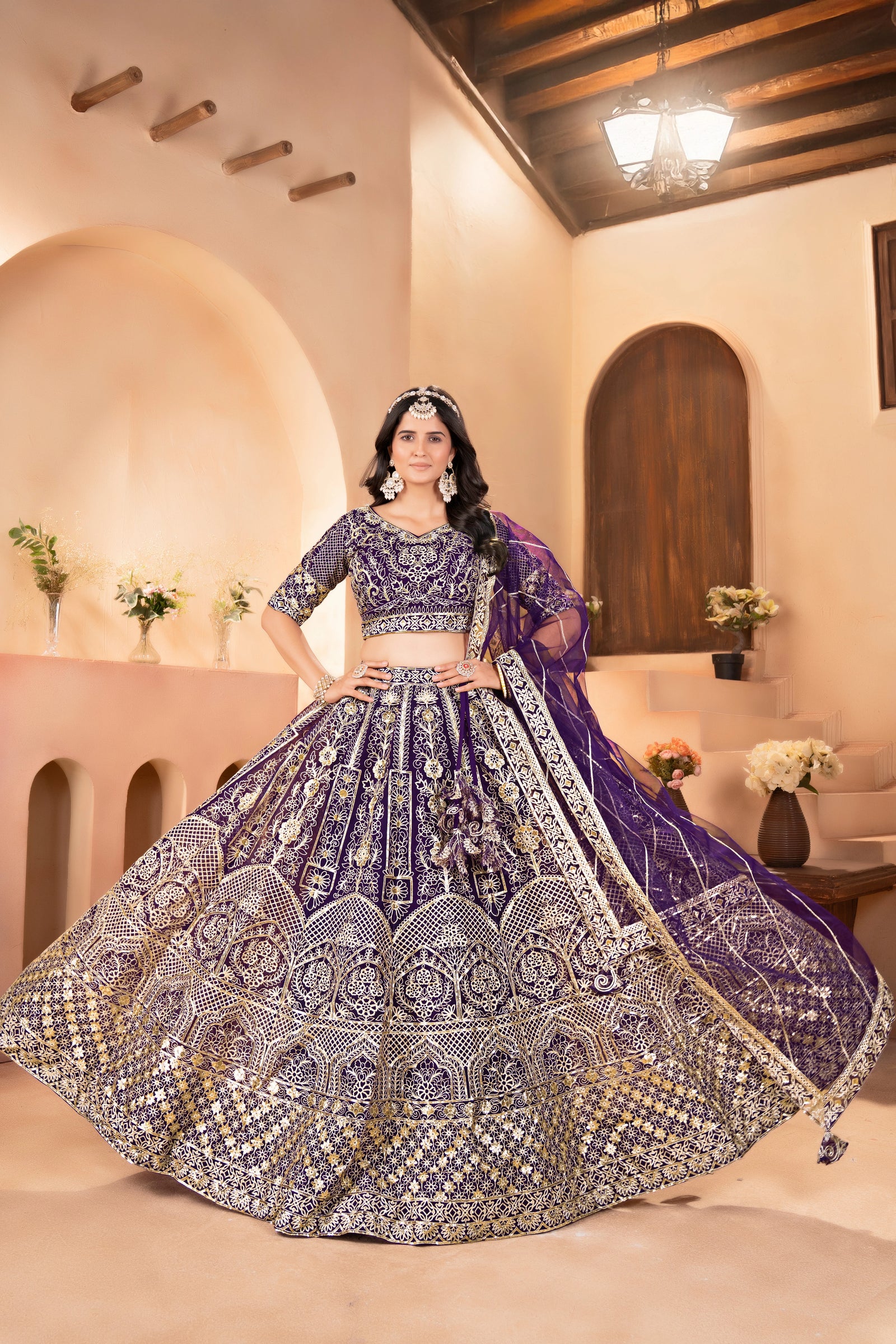 Woman in a traditional purple and gold embroidered outfit in an elegant indoor setting.