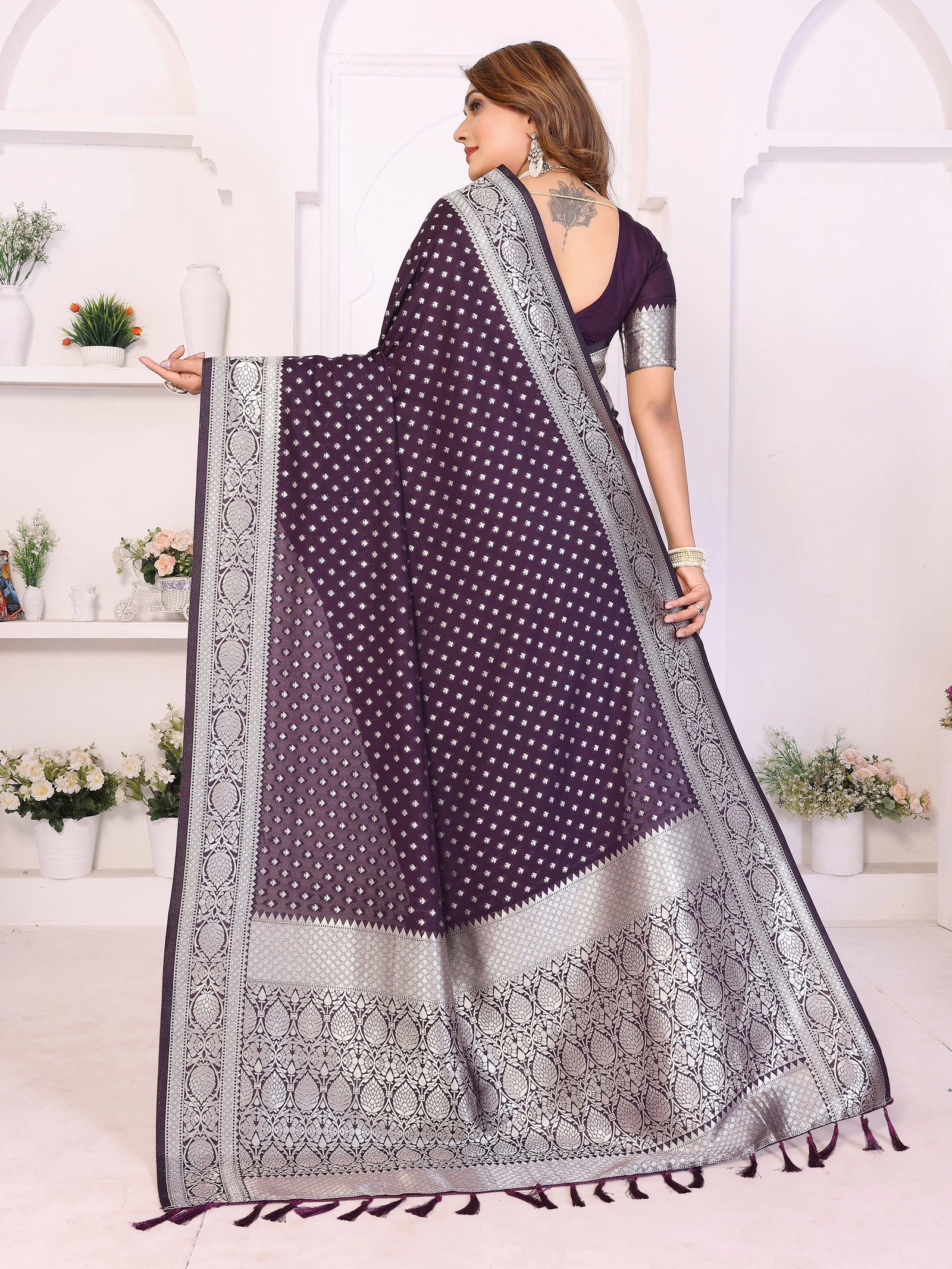 Woman wearing a purple saree with white patterns in a well-lit room.