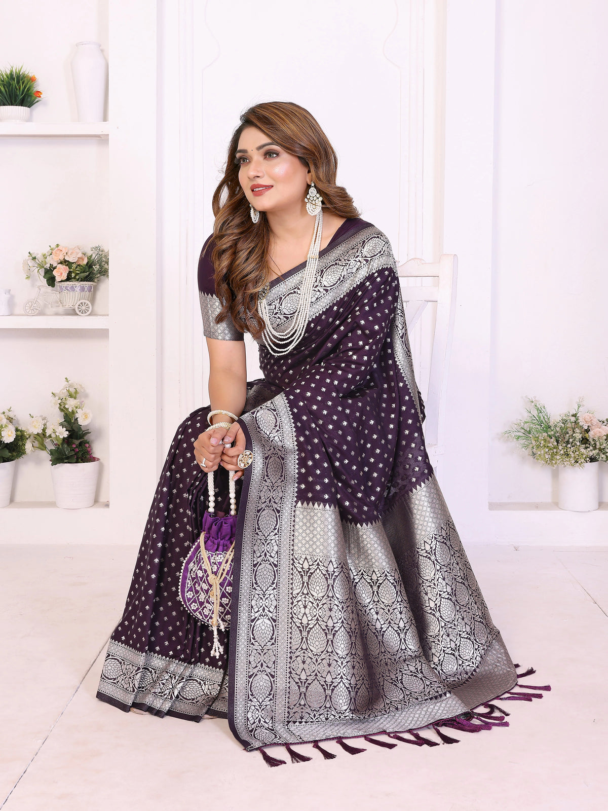 Woman wearing a purple and silver saree with a white background