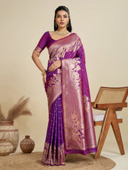 Woman wearing a purple saree with gold patterns in a minimalistic setting.