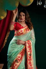 Woman wearing a traditional saree with a red blouse against a dark background