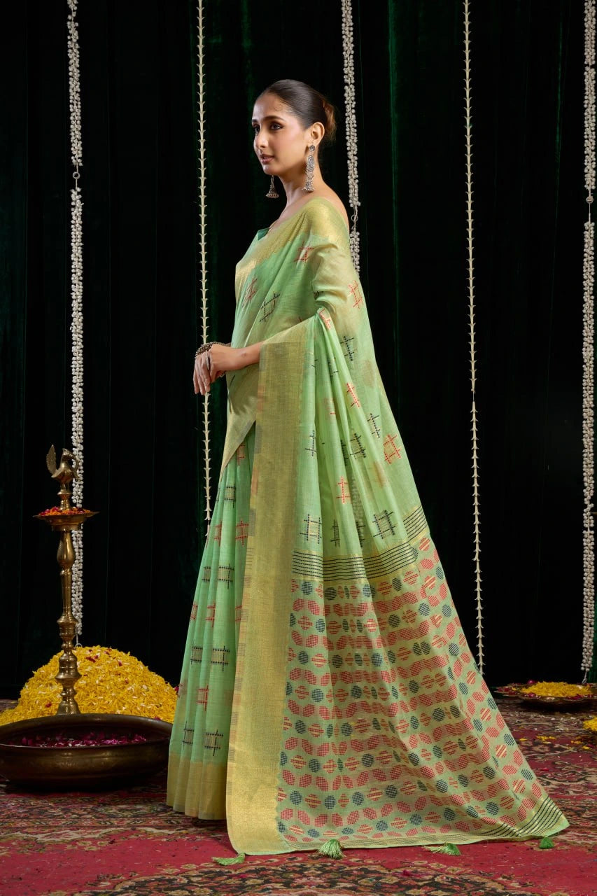 Woman in a green saree with a patterned design standing against a black background.