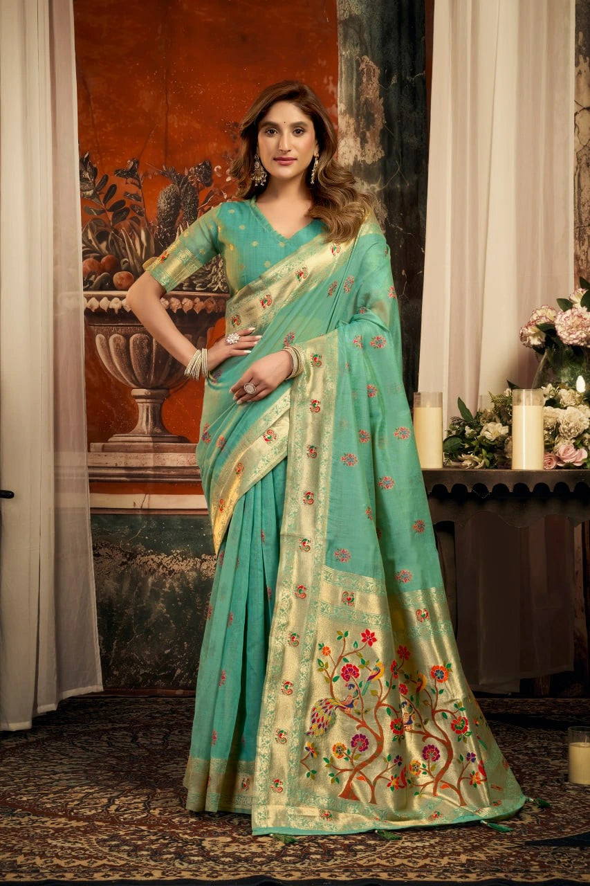 Woman wearing a teal saree with floral patterns in an indoor setting.