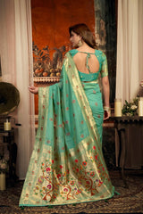 Woman in a light blue saree with floral patterns in an indoor setting.