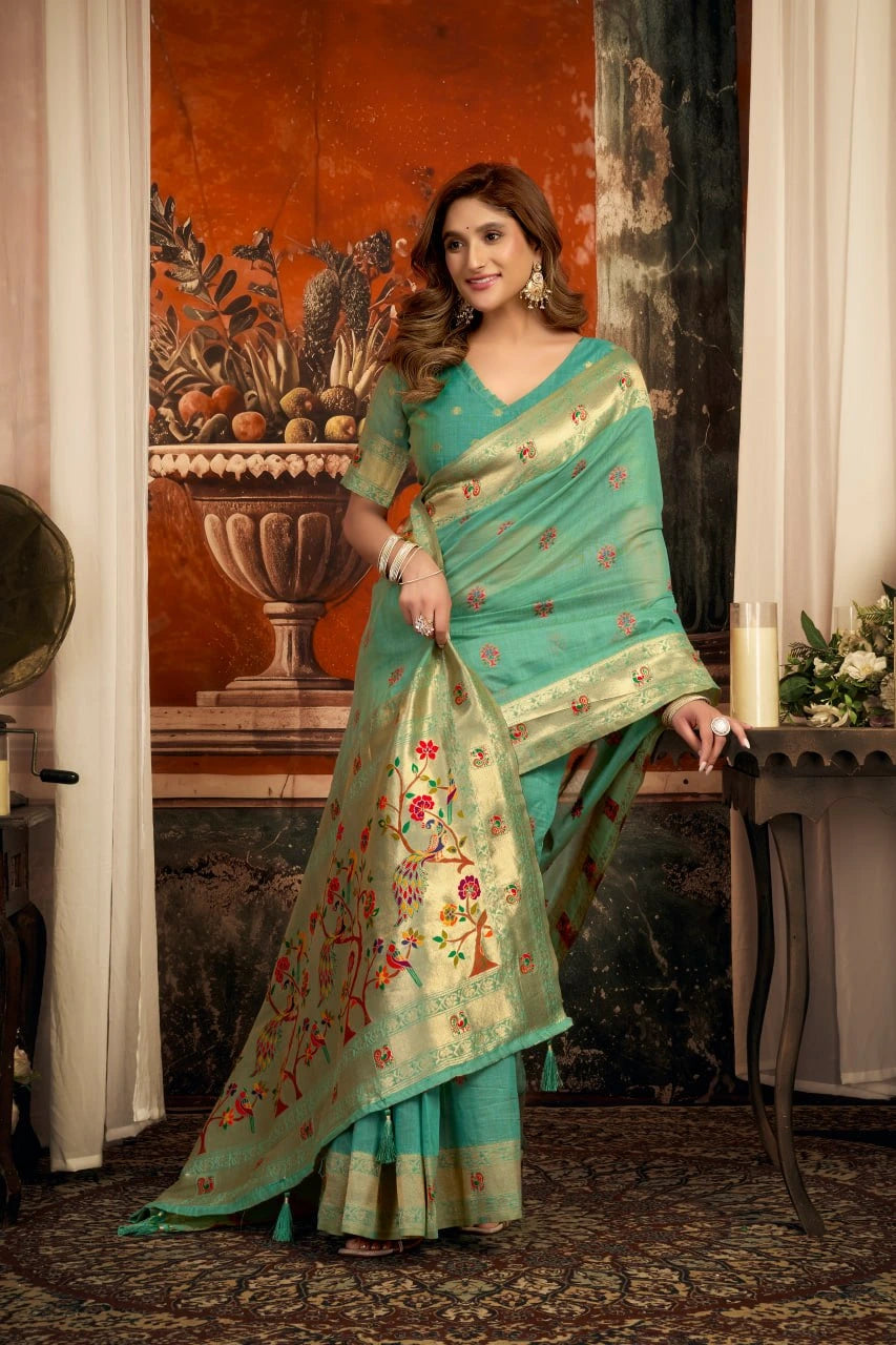 Woman in a green saree with floral patterns standing indoors.
