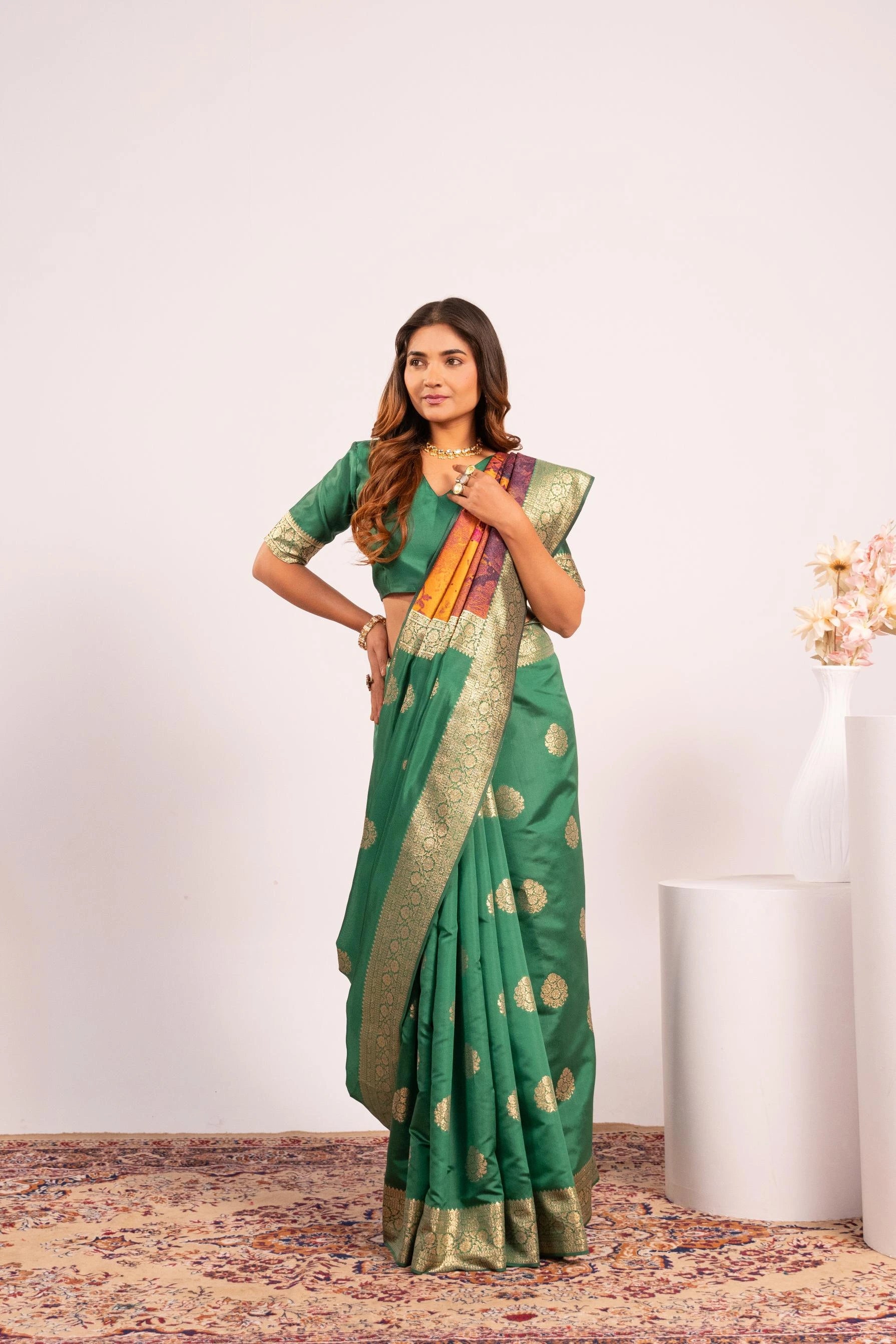 Woman wearing a green saree with gold patterns on a white background