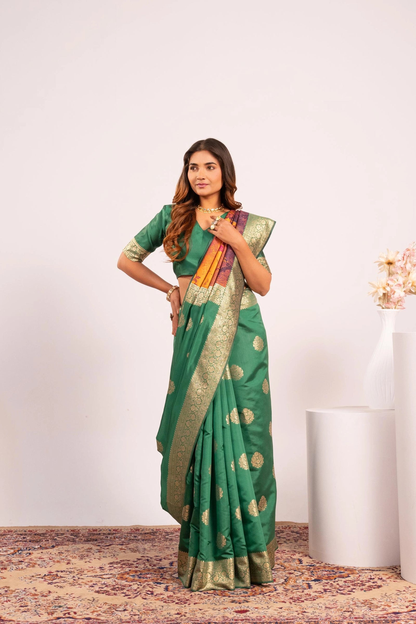 Woman wearing a green saree with gold patterns on a white background