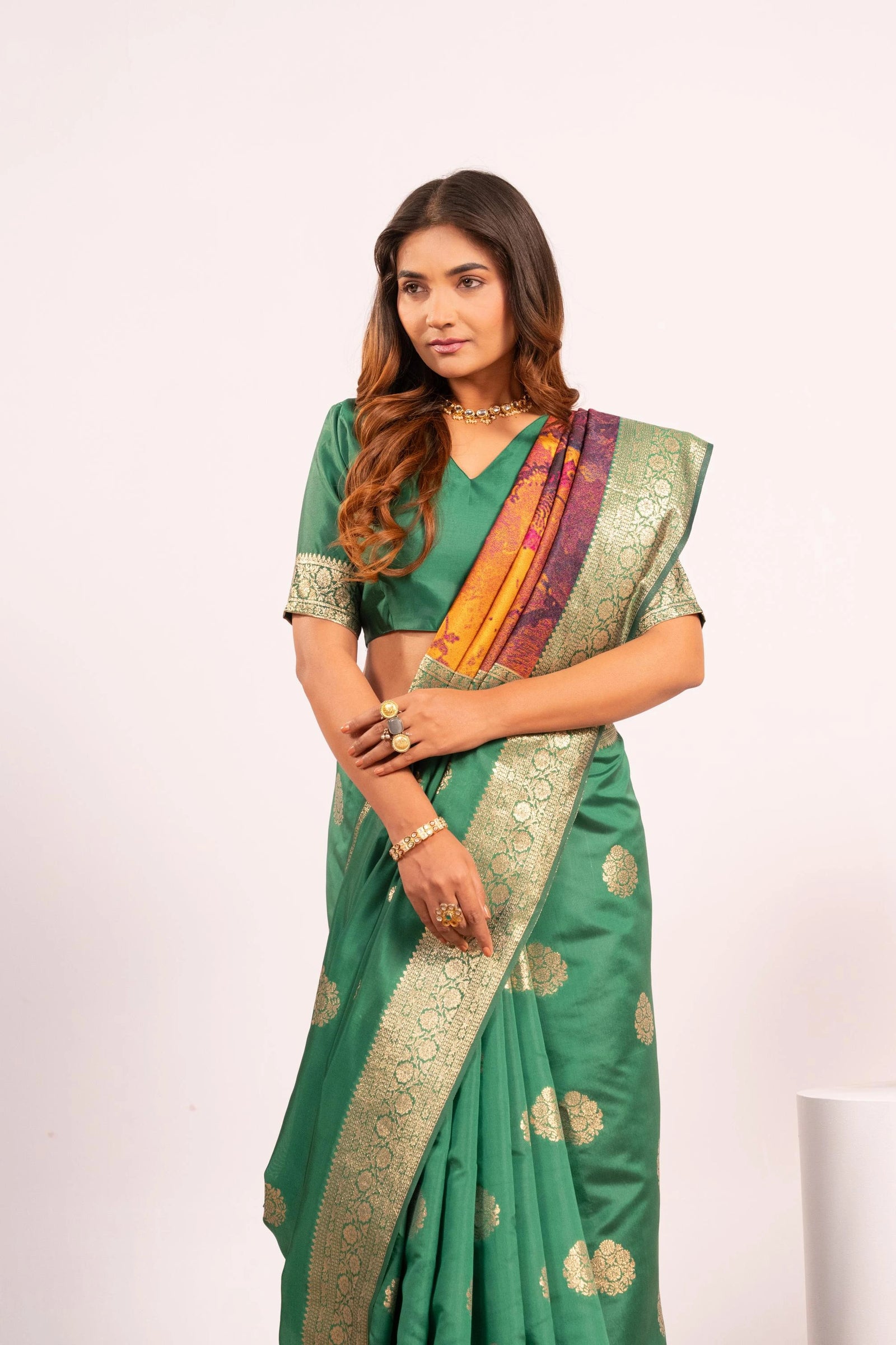 Woman wearing a green saree with gold patterns on a white background