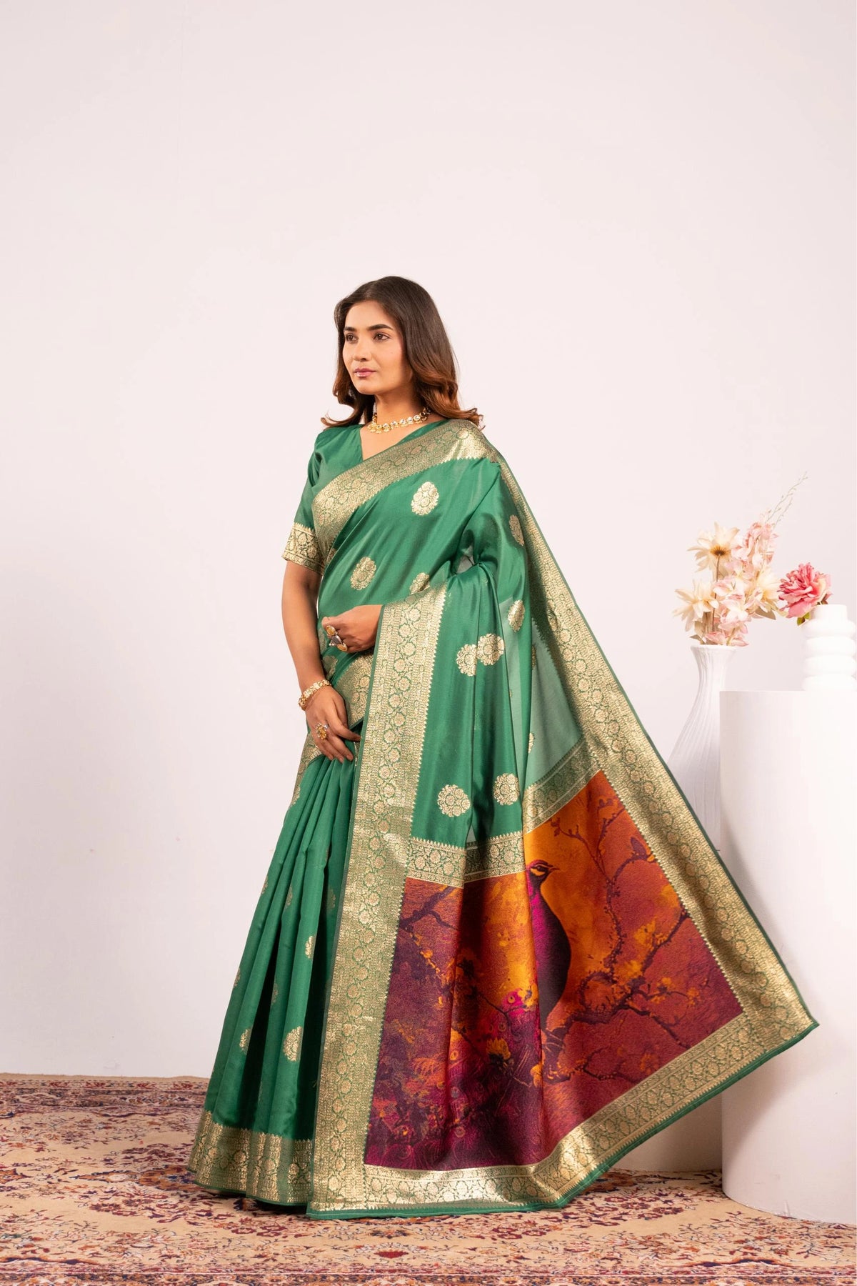 Woman wearing a green saree with a colorful border against a white background