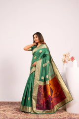 Woman wearing a green saree with a gold border and red and gold patterned blouse against a white background.