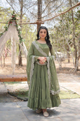 Woman in a green traditional outfit standing outdoors with trees in the background