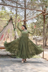 Woman in a green dress twirling outdoors with trees and decorations in the background