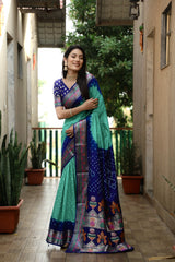Woman in a colorful saree standing in a corridor with plants.
