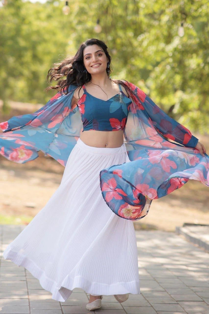 Woman in a blue floral top and white skirt with a colorful shawl outdoors.