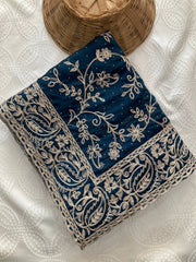 Navy blue fabric with intricate white embroidery on a textured white surface.
