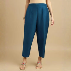 Teal pants worn by a person on a beige background