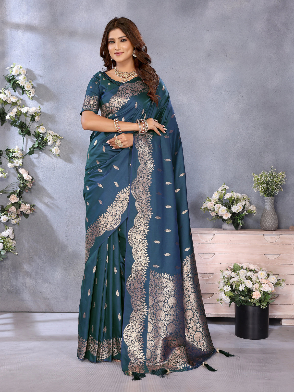 Woman wearing a blue saree with silver embroidery in a decorated room.