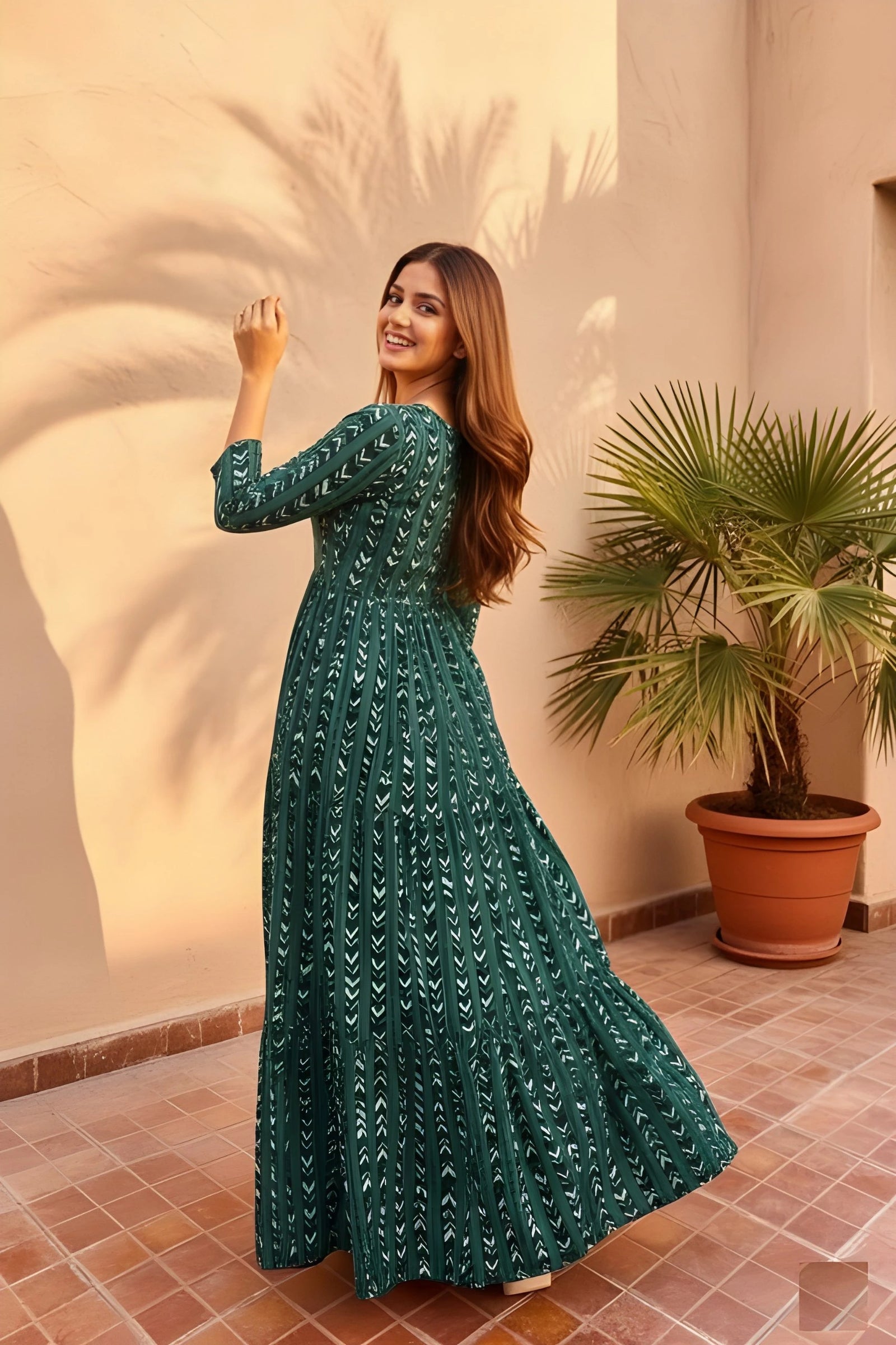 Woman in a green dress standing in a sunlit room with a plant in the background