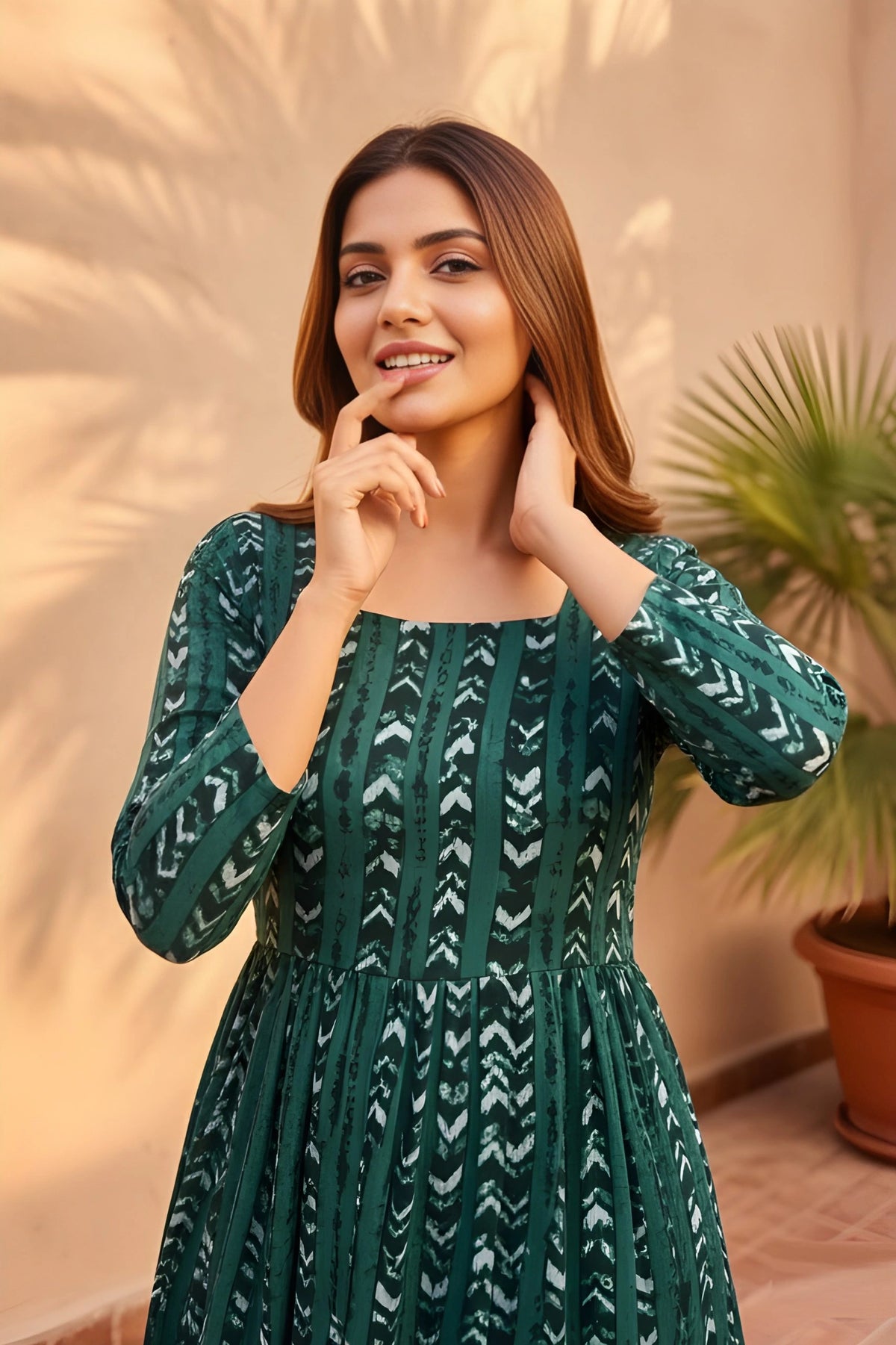 Woman wearing a green patterned dress standing outdoors with plants in the background