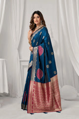 Woman wearing a blue and red saree with a white curtain background
