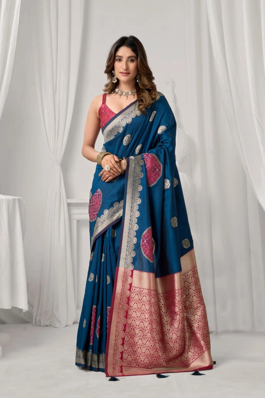 Woman wearing a blue saree with pink patterns against a white curtain background