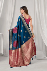 Woman wearing a blue and pink saree with a white curtain background