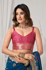 Woman wearing a red blouse and blue saree with jewelry against a white background