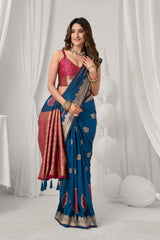Woman wearing a blue saree with gold patterns against a white curtain background