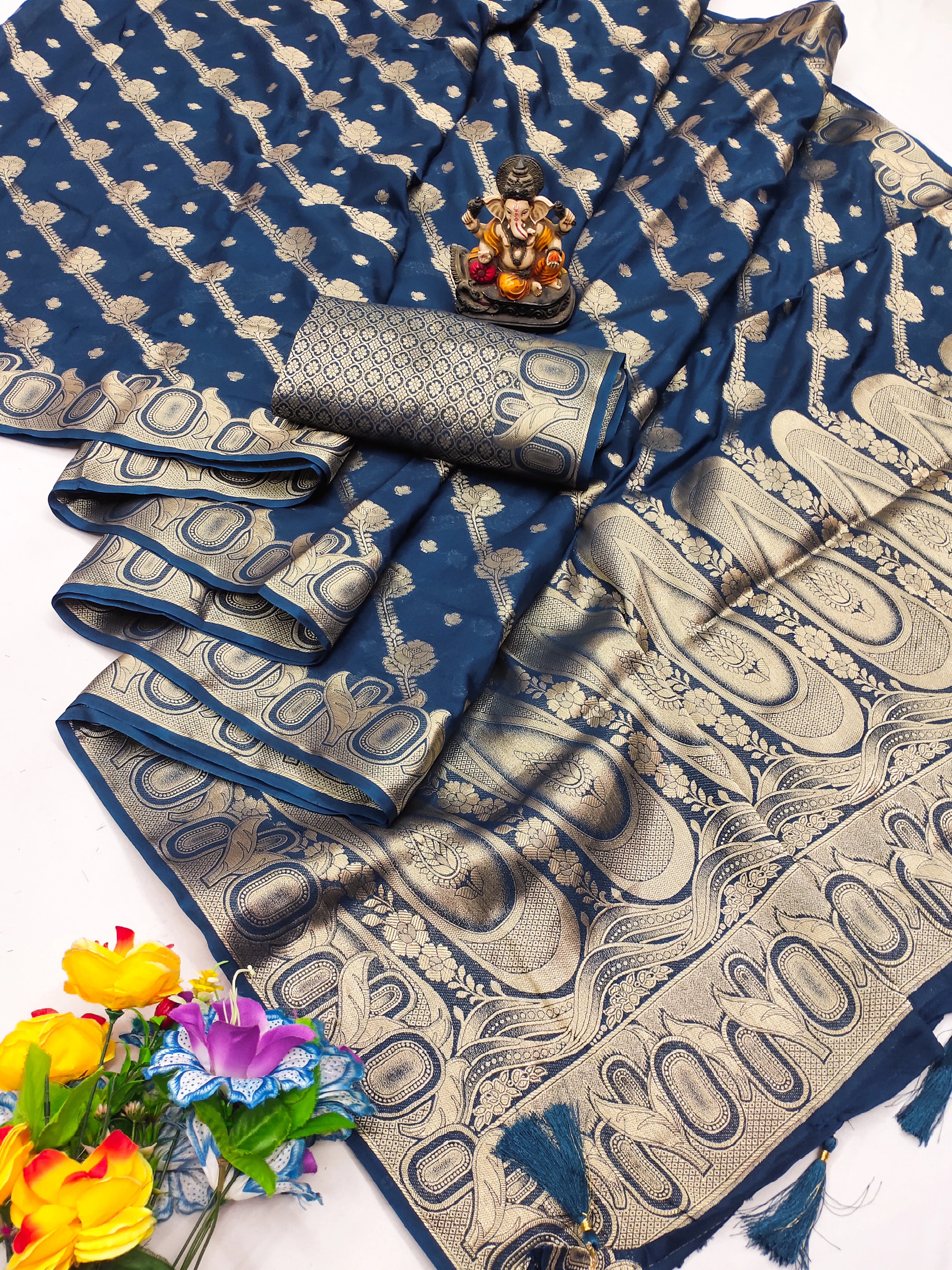 Blue and beige patterned saree with a small statue and flowers on a white background