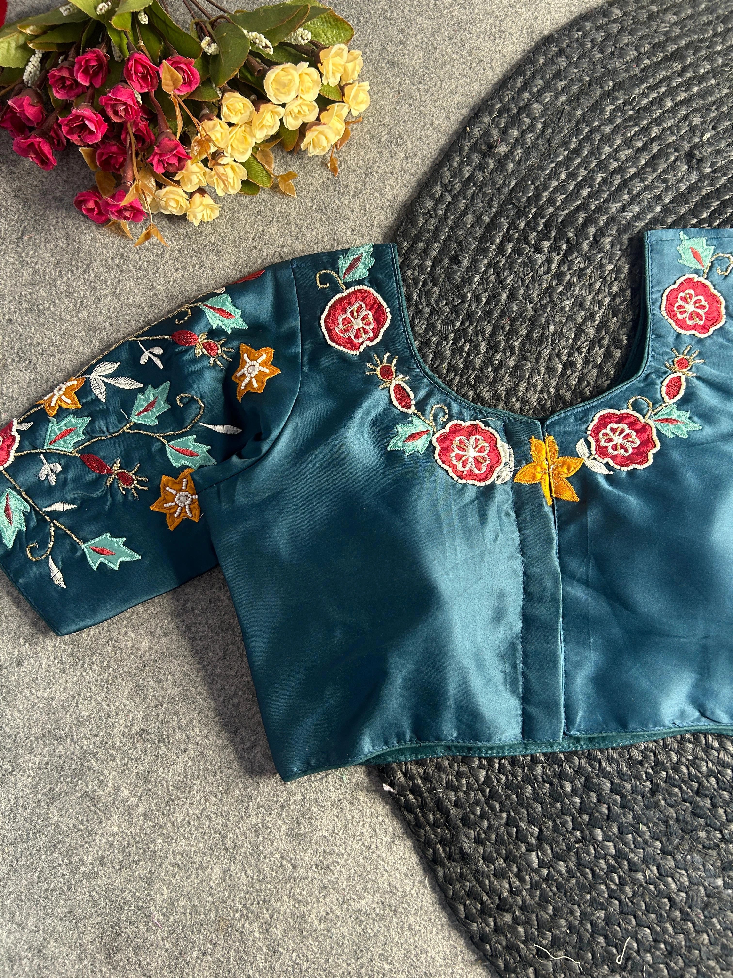 Back view of the teal blouse, showcasing a centered hook-and-eye closure. The floral and leaf embroidery continues along the rear neckline and across the sleeves, highlighted by the subtle sheen of the dark teal fabric.