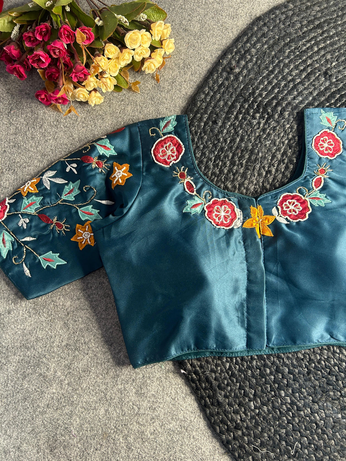 Back view of the teal blouse, showcasing a centered hook-and-eye closure. The floral and leaf embroidery continues along the rear neckline and across the sleeves, highlighted by the subtle sheen of the dark teal fabric.