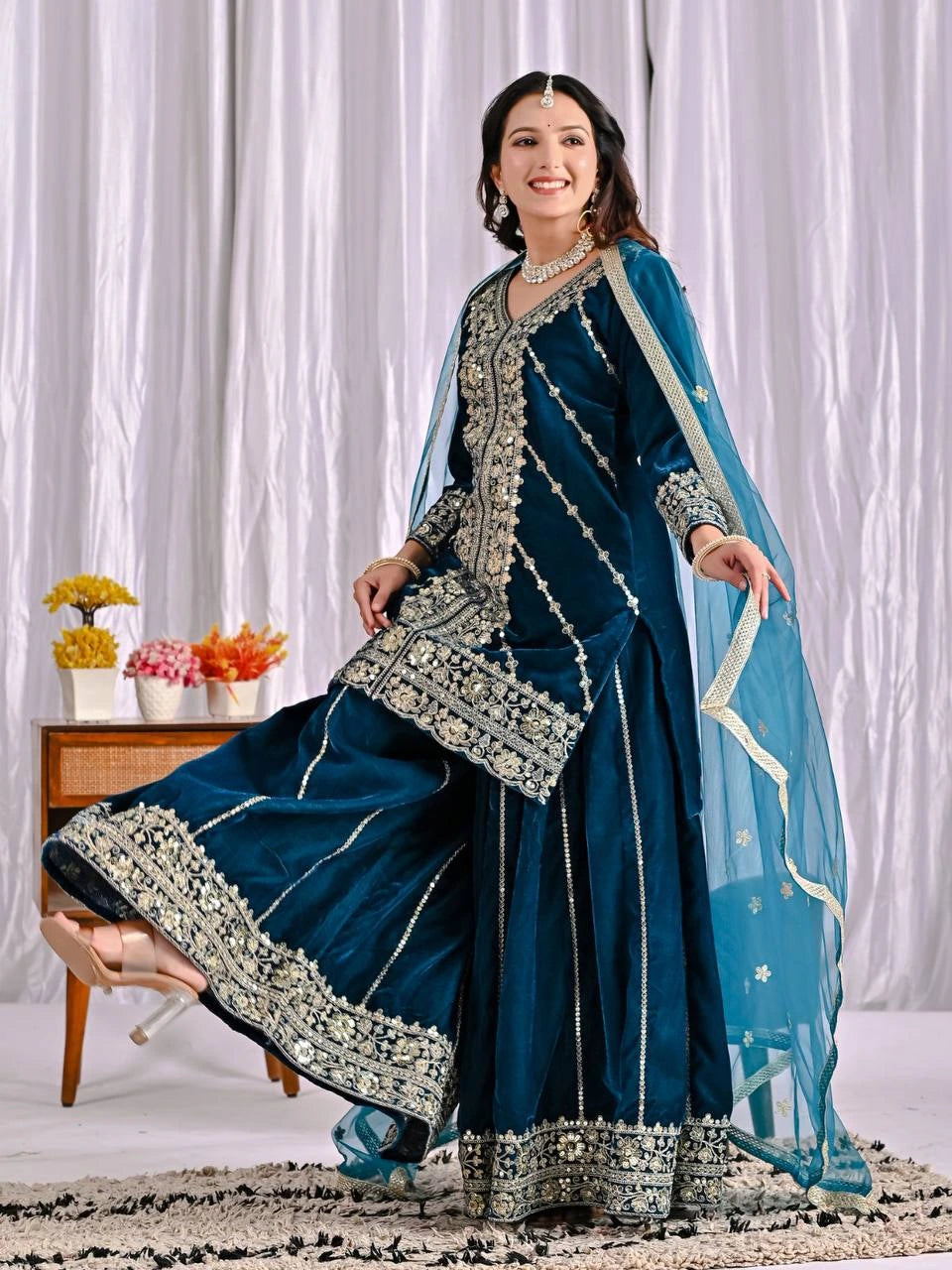 Woman in a traditional blue embroidered outfit with a white curtain background