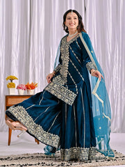 Woman in a traditional blue embroidered outfit with a white curtain background
