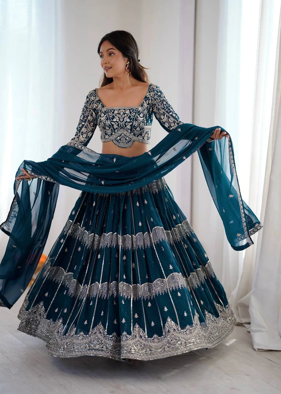 Woman in a traditional blue and silver lehenga with a white curtain background