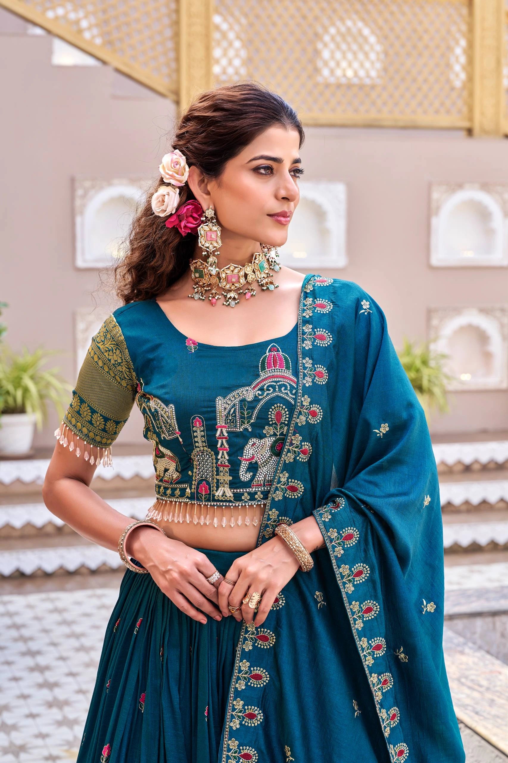 Woman wearing a traditional blue embroidered outfit with floral accessories.