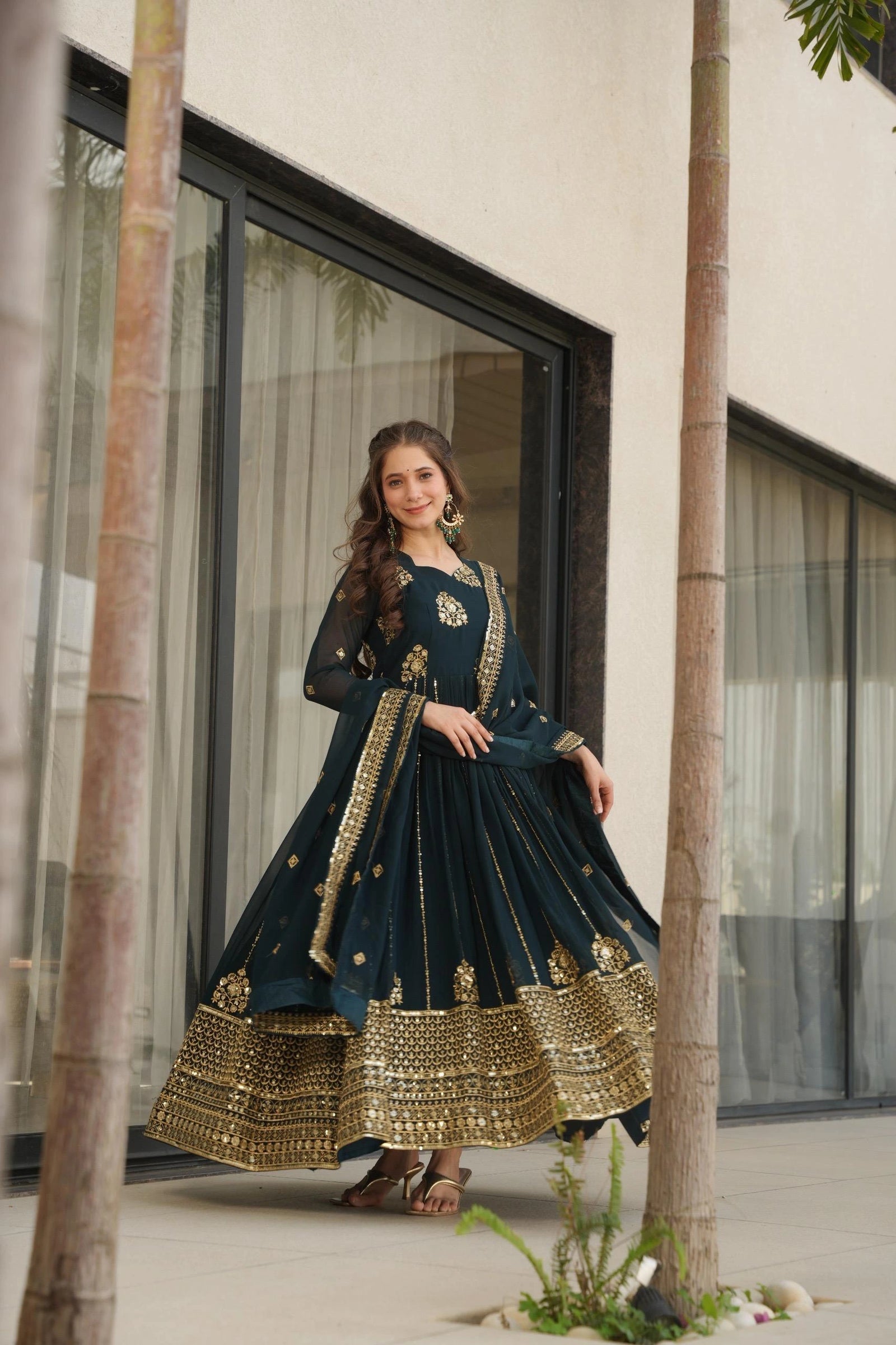 Woman in a dark blue traditional outfit with gold details standing outdoors.