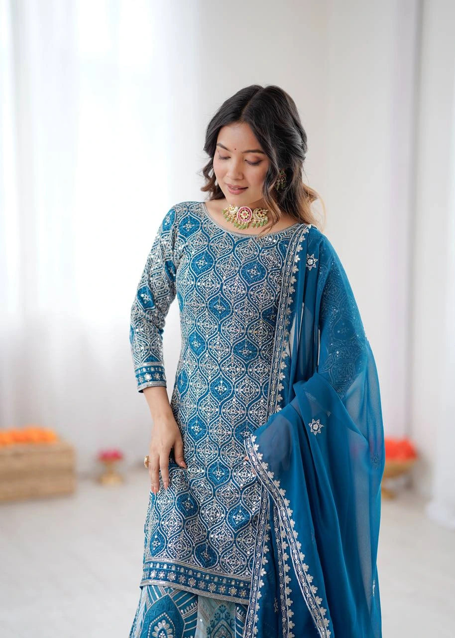Woman wearing a blue and white patterned outfit with a matching dupatta in a bright room.