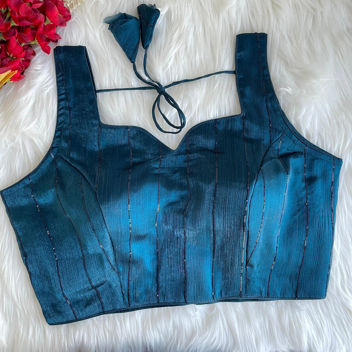 Blue top on a white fluffy surface with floral decorations