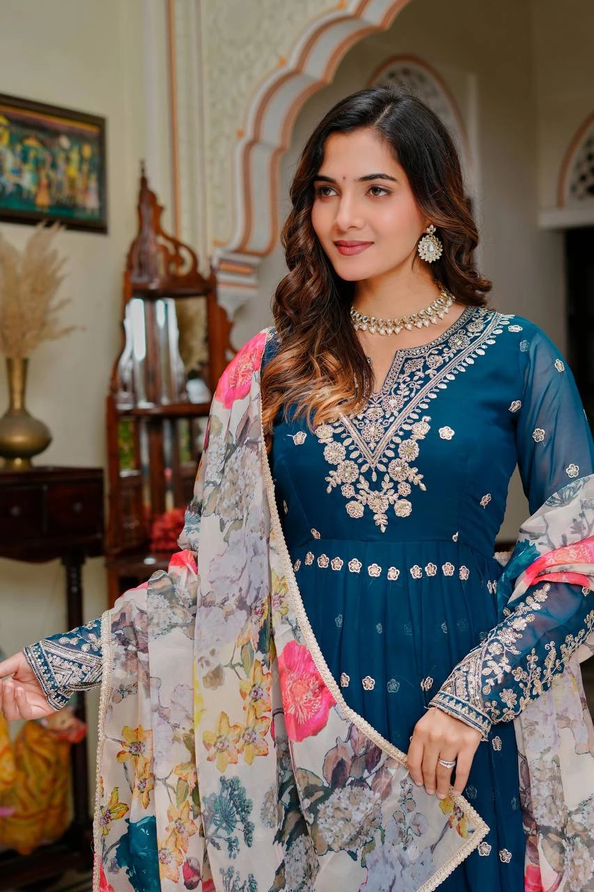 Woman in a blue embroidered dress with a floral dupatta in an indoor setting
