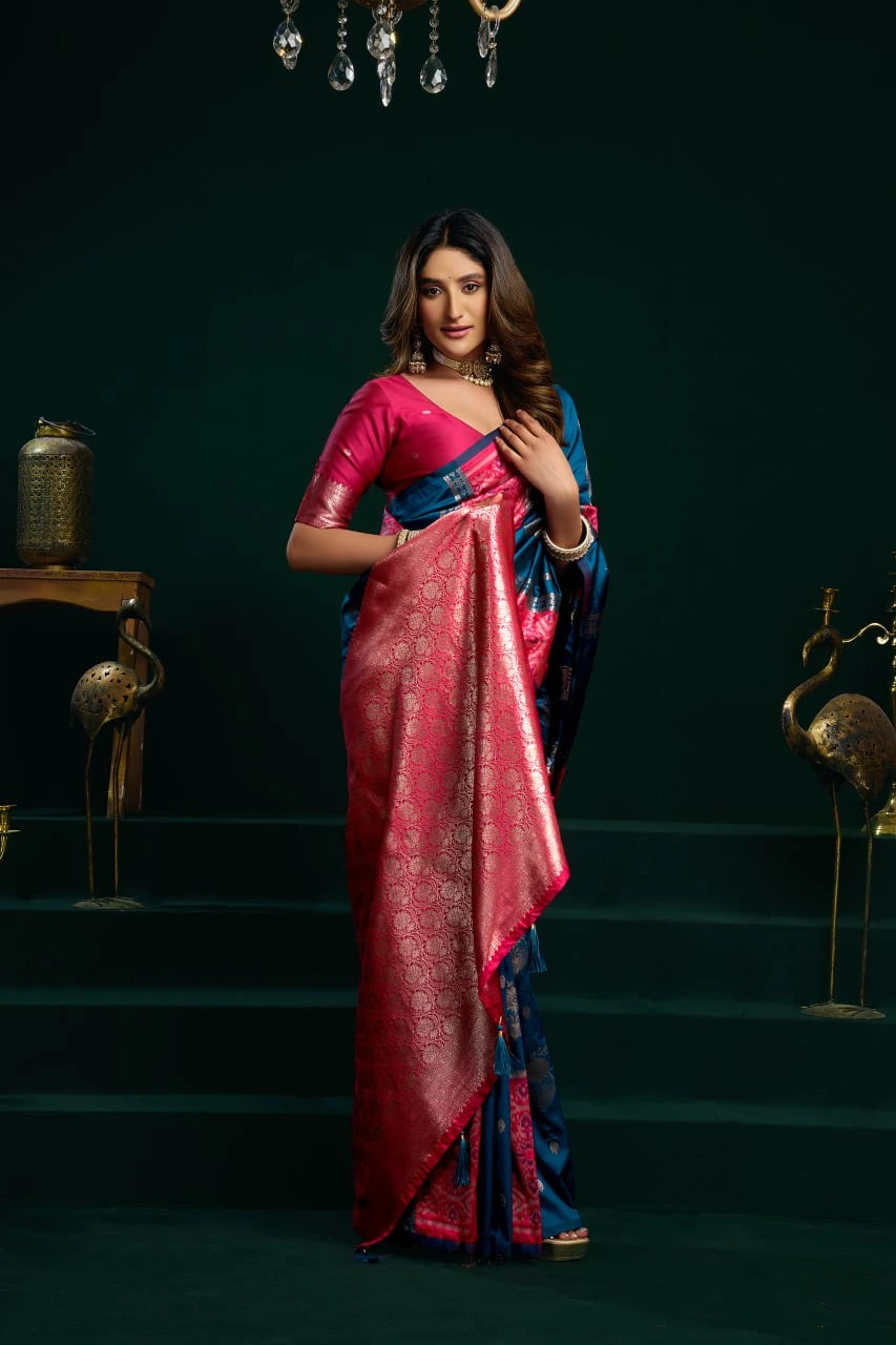 Woman in a red and blue saree standing on a dark staircase.