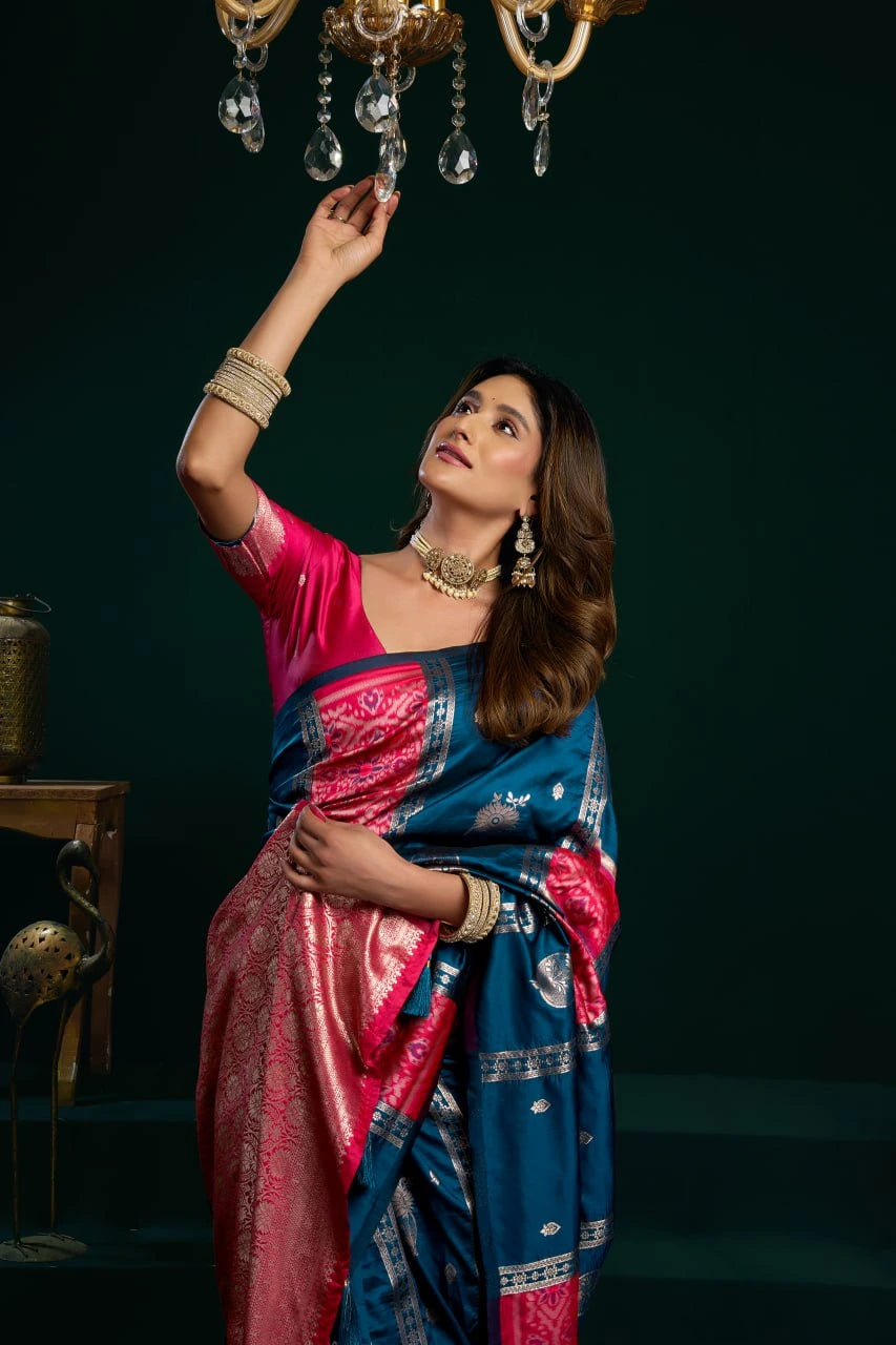 Woman in a traditional saree adjusting a chandelier against a dark background