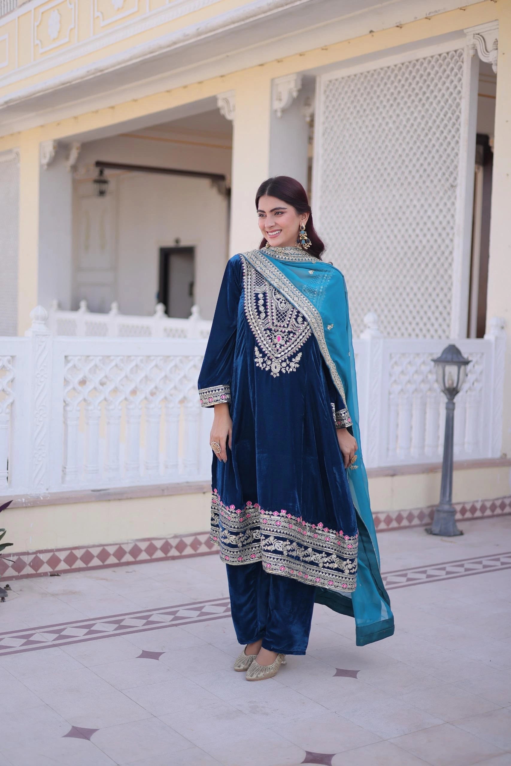Woman in a blue and white traditional outfit standing in front of a decorative building.