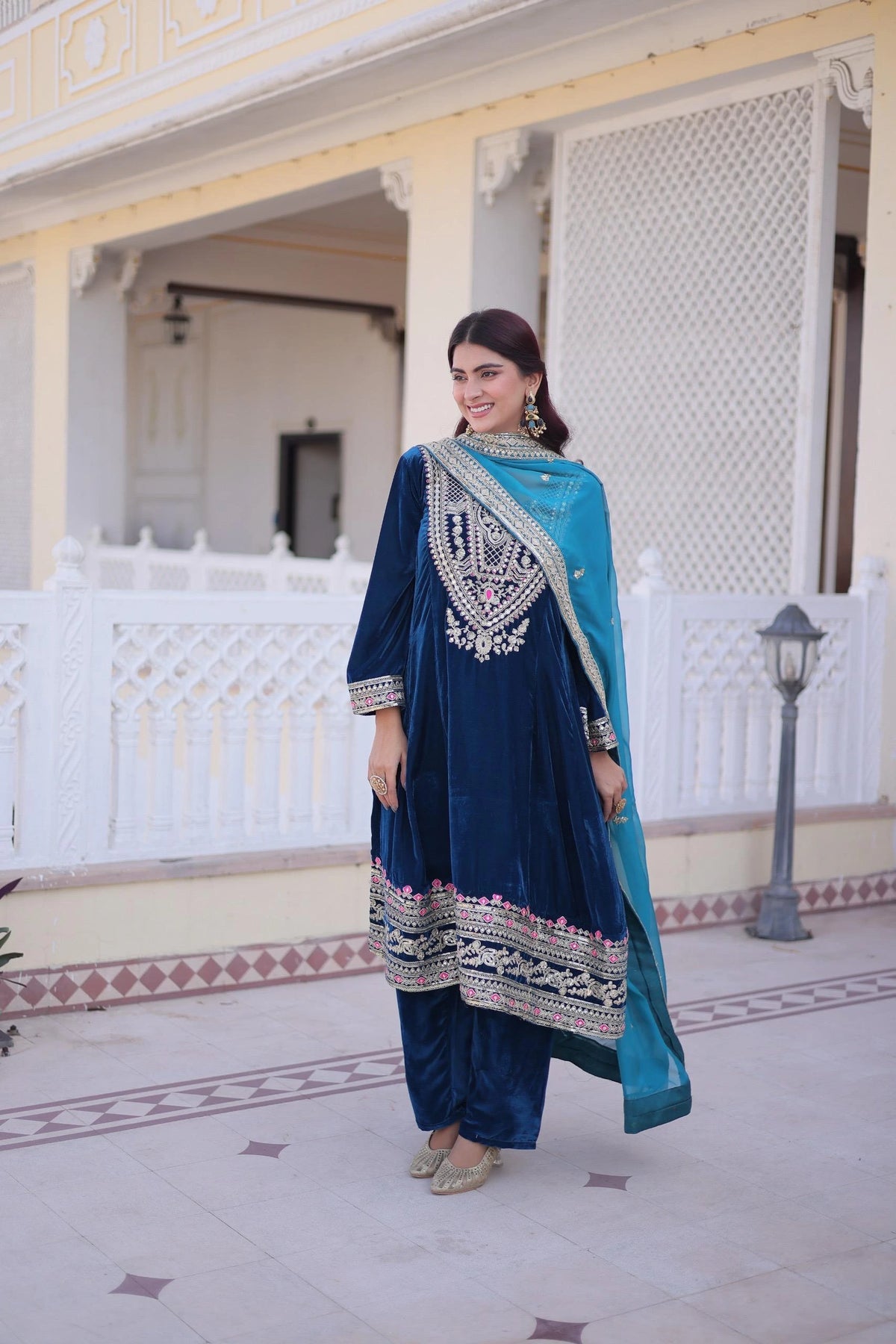 Woman in a blue and white traditional outfit standing in front of a decorative building.