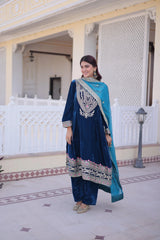 Woman in a blue and white traditional outfit standing in front of a decorative building.