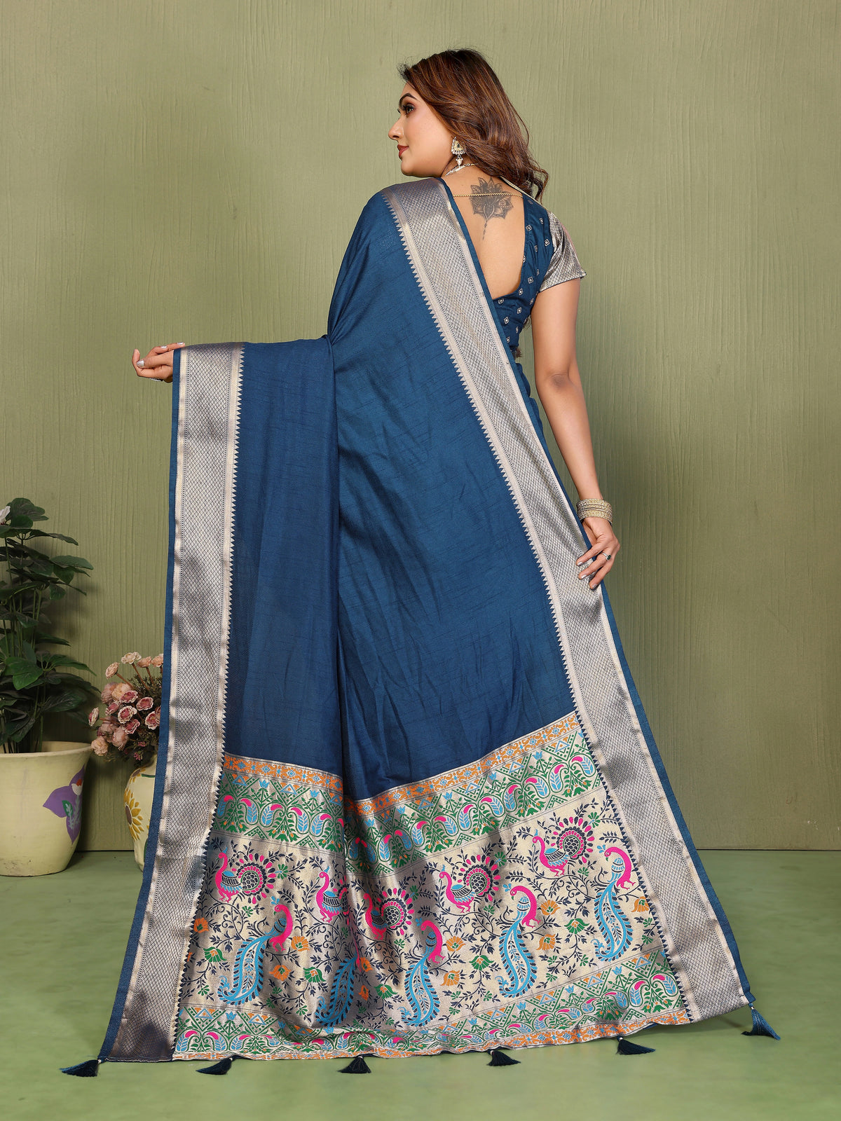 Woman wearing a blue saree with a patterned border on a green background